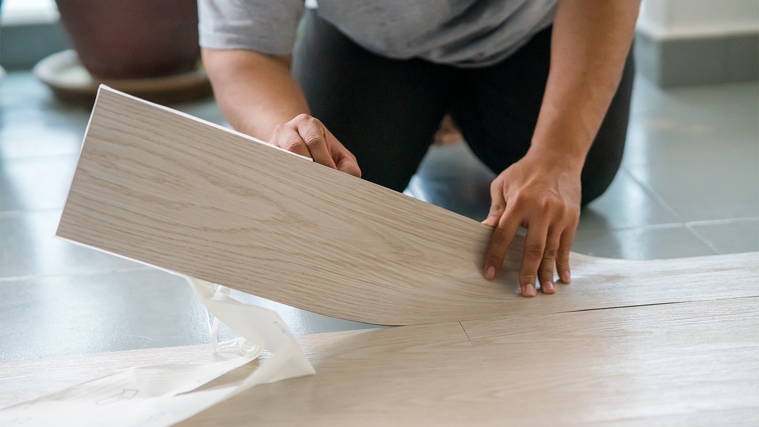 man applying peel and stick vinyl to floor